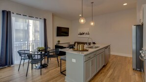 Une cuisine moderne dotée d’un îlot central, de luminaires suspendus et d’un coin repas avec une table et des chaises.