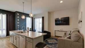 Une cuisine moderne dotée d’un îlot central, de luminaires suspendus et d’une grande fenêtre.