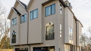 Un immeuble résidentiel de deux étages, doté d’un garage, d’une allée et d’une cour pavée.