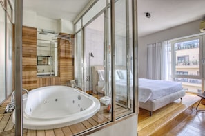 Ein modernes Hotelzimmer mit einer großen Badewanne, einem Bett und einem Balkon mit Blick.
