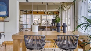 A modern dining area with a wooden table, grey chairs, and potted plants. - Sunny Luxury Loft, Stunning Acropolis View, Jacuzzi (Athina)