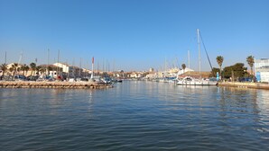 A marina with boats docked, a clear sky, and buildings in the background.