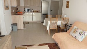 A compact living space with a kitchenette, dining area, and a sofa with a floral pillow.