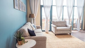 A living room with a blue wall, two sofas, a small round table, and a potted plant.