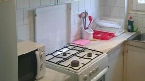 Una cocina con gabinetes blancos, estufa a gas, microondas y fregadero.