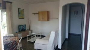 Una habitación con cama, una mesita, una silla, un armario y una televisión.
