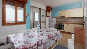 Eine kompakte Küche mit Essbereich, inklusive Tisch mit gemustertem Tischläufer, Kühlschrank und Herd.