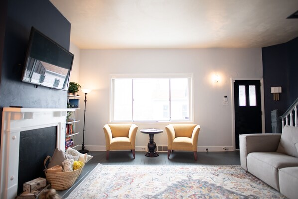 A living room with a fireplace, two armchairs, a sofa, a patterned rug, and a large window. - Skyline Views & Adventure ★ Dogs 👍 ★ Professionally Cleaned ★ Close to all!  (Pittsburgh)