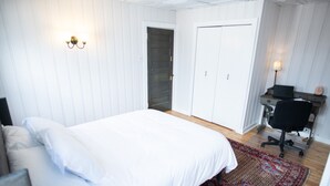 Una camera da letto con un letto grande, una scrivania con una sedia e una porta che dà su un'altra stanza.