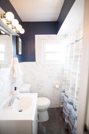 A bathroom with a white sink, toilet, and marble walls. - Skyline Views & Adventure ★ Dogs 👍 ★ Professionally Cleaned ★ Close to all!  (Pittsburgh)