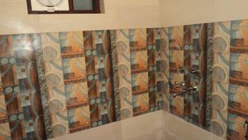 Un baño con pared de baldosas estampadas y una bañera.
