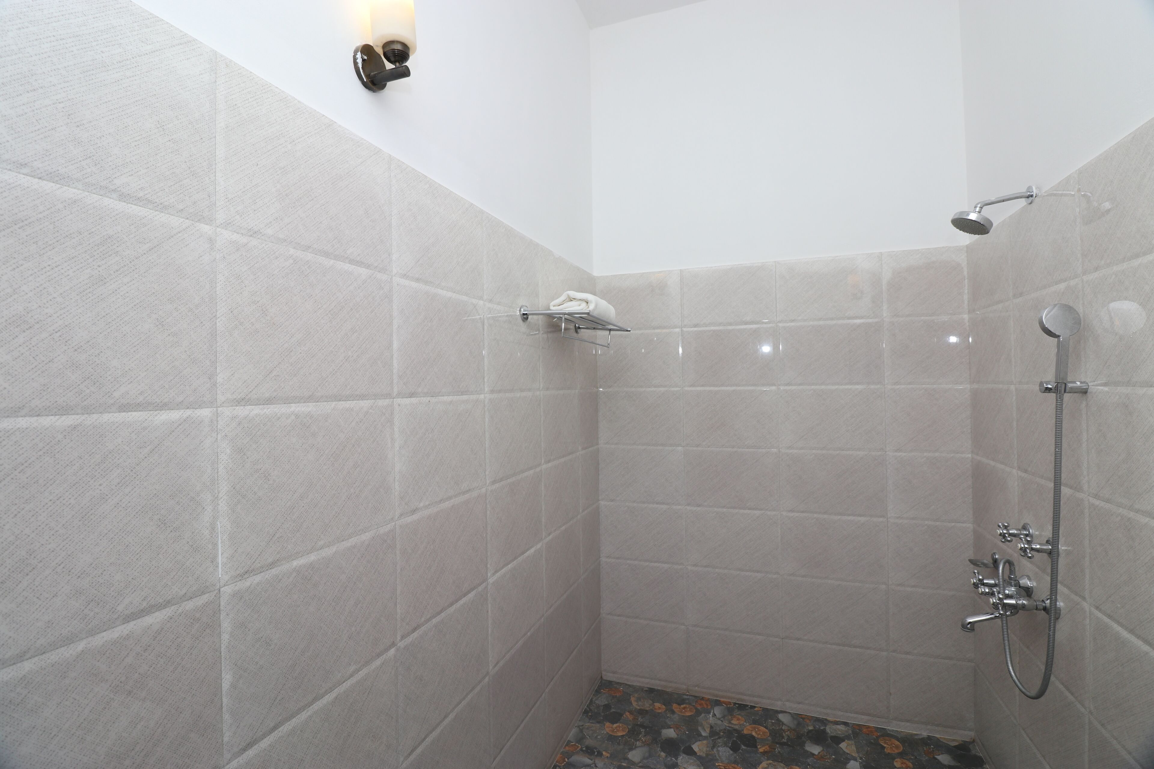 Una ducha moderna con cabezal de ducha manual y grifo empotrado en la pared.