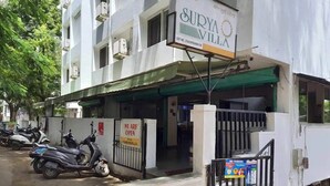 Hotel Surya Villa, con un letrero, entrada vigilada y scooters estacionados.