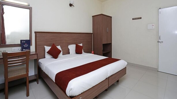 Un dormitorio ordenado con cama, escritorio, armario y una puerta blanca.