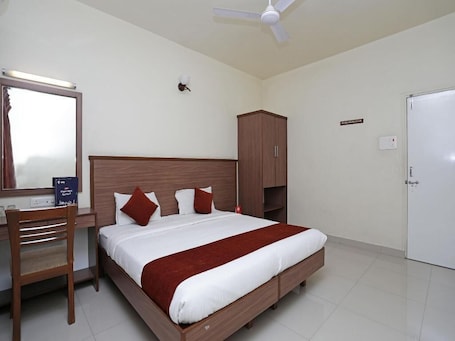 A neatly arranged bedroom with a bed, a desk, a wardrobe, and a white door.