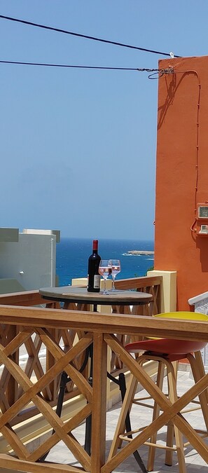 Una terraza con una mesa y sillas, una botella de vino y una copa sobre la mesa.