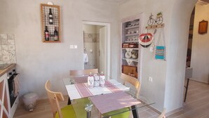 A kitchen with a glass table, chairs, and a wine rack. There is a door leading to another room.
