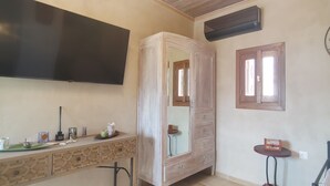 A bedroom with a bed, a dresser, a vanity, a television, a mirror, and a window.