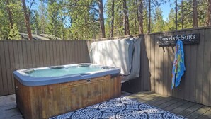 A wooden hot tub with a wooden deck, a towel hanging on the wall, and a sign that reads "Towels & Suits". - 13 Timber-Sunriver, Oregon: Hot Tub, BBQ, WiFi, SHARC Aquatics, Tubing Hill, Mt. Bachelor, Golf, Deschutes River, Tennis, Bike Paths (Sunriver)