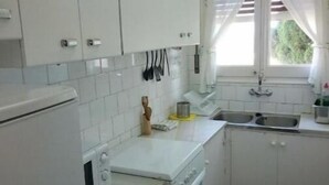 Een kleine keuken met witte kastjes, een fornuis en een spoelbak.