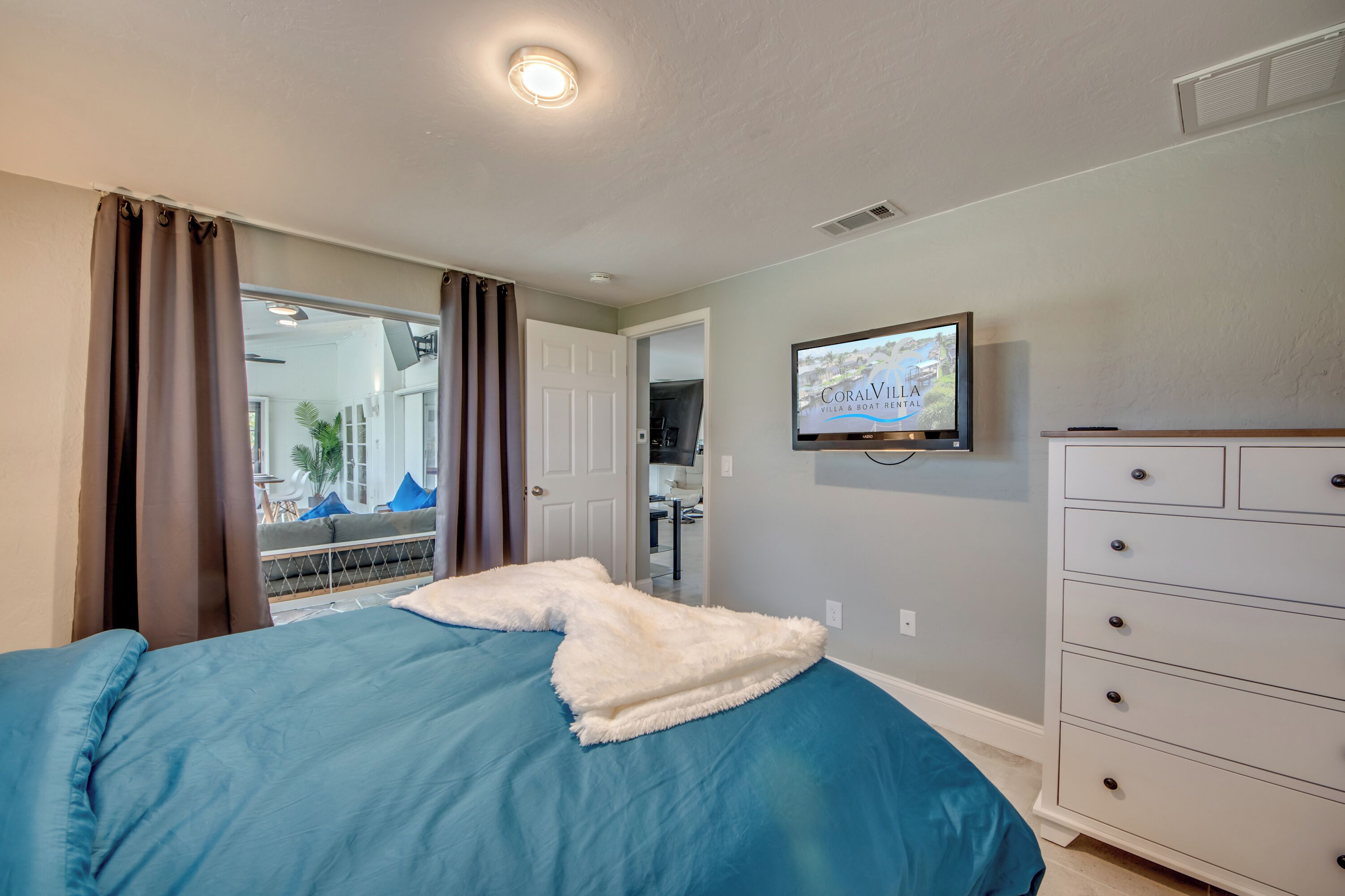 A bedroom with a bed, a TV mounted on the wall, and a dresser.