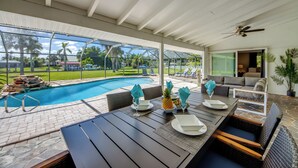 An outdoor patio with a pool, dining table, and seating area. - Villa Seafan - remodeld, new furniture, heated pool, kayaks, perfect for boaters (North Fort Myers)