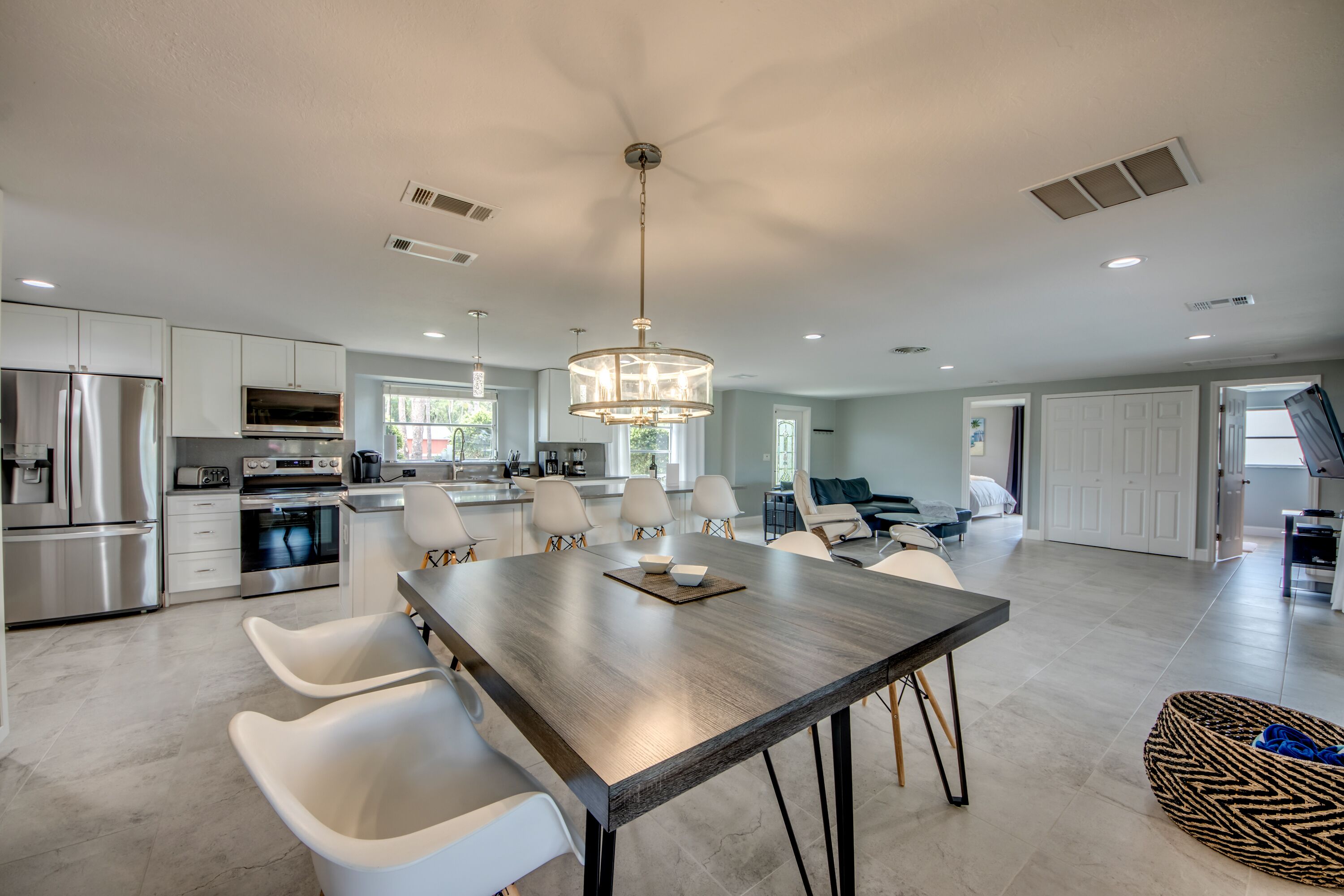 A spacious kitchen with modern appliances, a dining area with a large table and chairs, and a living area with a sofa and a TV.