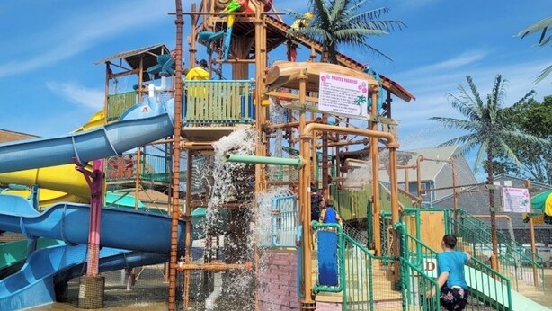 Een waterpark met een meerlaags speelconstructie, glijbanen en waterattracties.