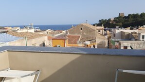 A rooftop terrace with a view of the sea and surrounding buildings.