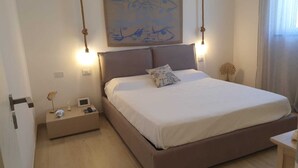 A bedroom with a large bed, bedside tables, a wall-mounted artwork, and a bedside lamp.