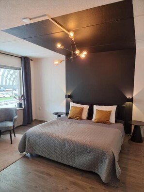A modern bedroom with a large bed, a dark accent wall, and a ceiling light fixture. - Studio Trenz for two - Groningen Center (Groningen)