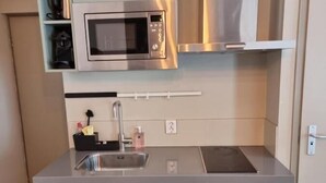 A compact kitchen with a built-in microwave, a sink, and cabinets. - Studio Trenz for two - Groningen Center (Groningen)
