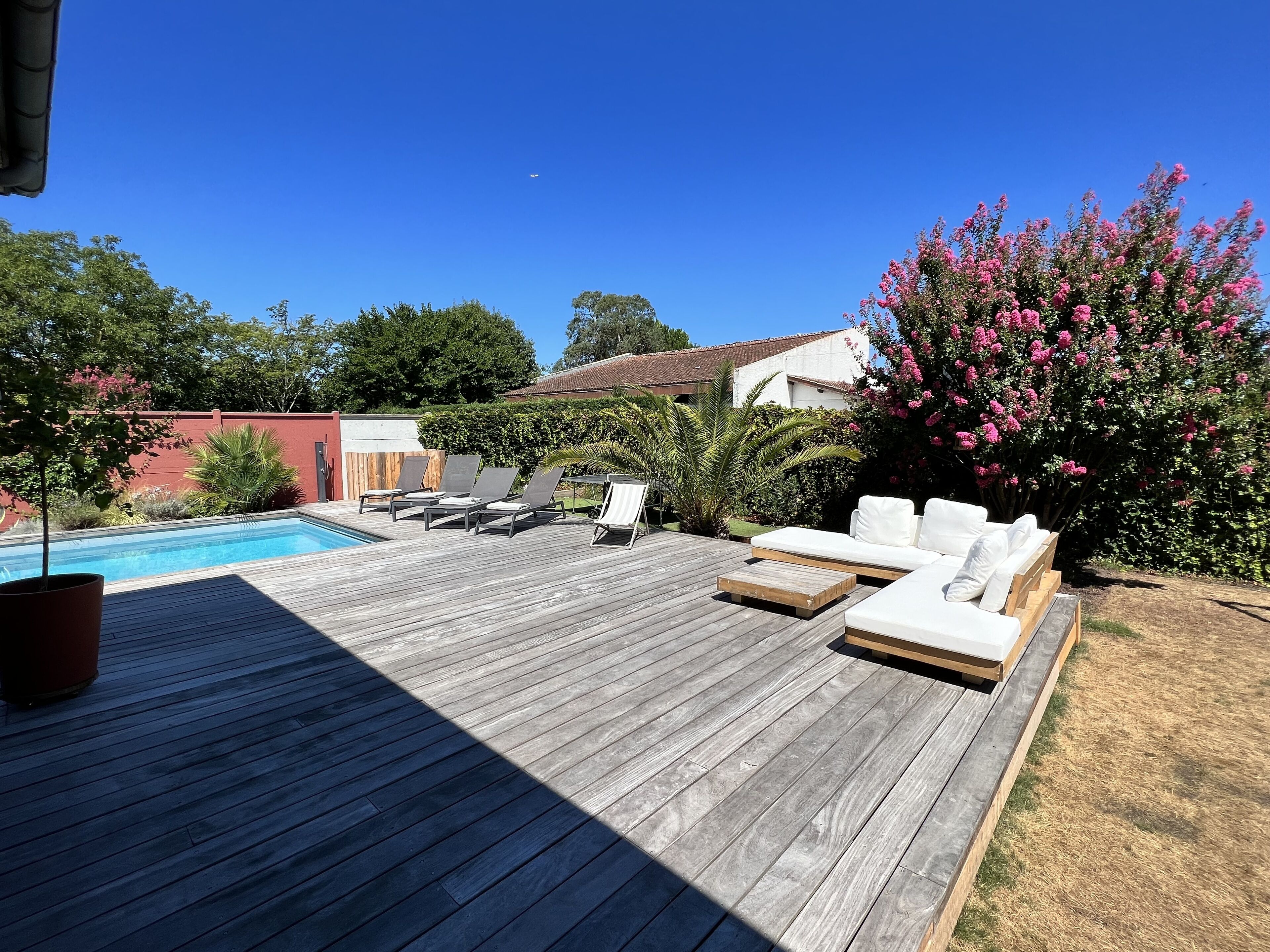 Een houten terras met loungezetels en een zwembad.