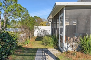Stroll through the beautifully maintained garden, leading to the entrance of this serene home with a large window and screen door.