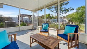 Un patio techado al aire libre con mobiliario de madera, que incluye una mesa y dos sillas con cojines azules.