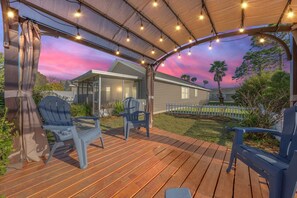 A covered deck with wooden flooring and two blue chairs. - Good Vibes PCB- Private and Serene Getaway (Panama City Beach)