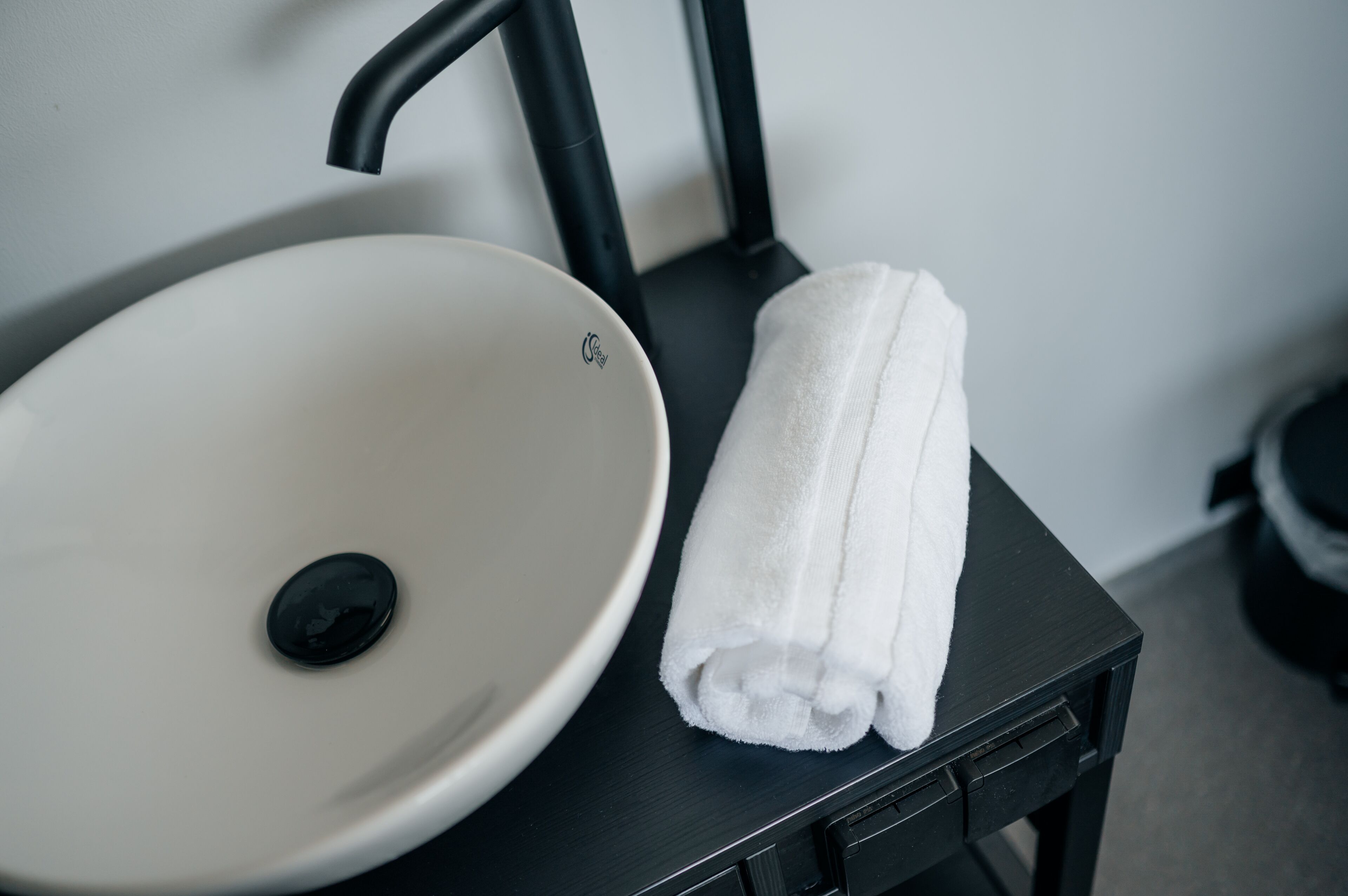 A white sink with a black faucet on a black table.