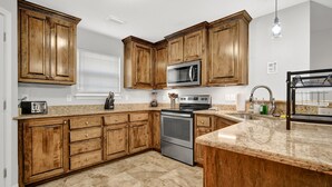 Eine Küche mit Holzausstattung, einer Mikrowelle, einem Backofen und Granit Arbeitsplatten.
