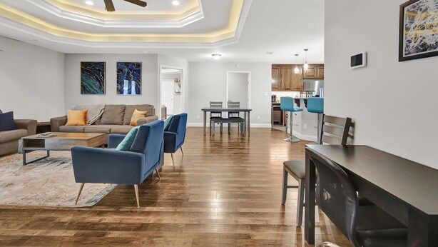 Ein geräumiges Wohnzimmer mit Holzboden, Deckenventilator und einem Essbereich mit Tisch und Stühlen.