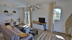 Een moderne woonkamer met een bank, salontafel, televisie en eethoek.