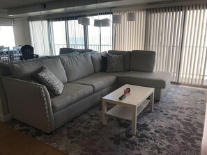 Un salon moderne avec un canapé d’angle, une table basse et un coin repas à l’arrière-plan.