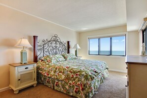 A bedroom with a bed, nightstand, dresser, and a window with a view.
