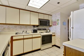 Kitchen features a central island with a sink, toaster, and microwave, along with a refrigerator and tiled backsplash.