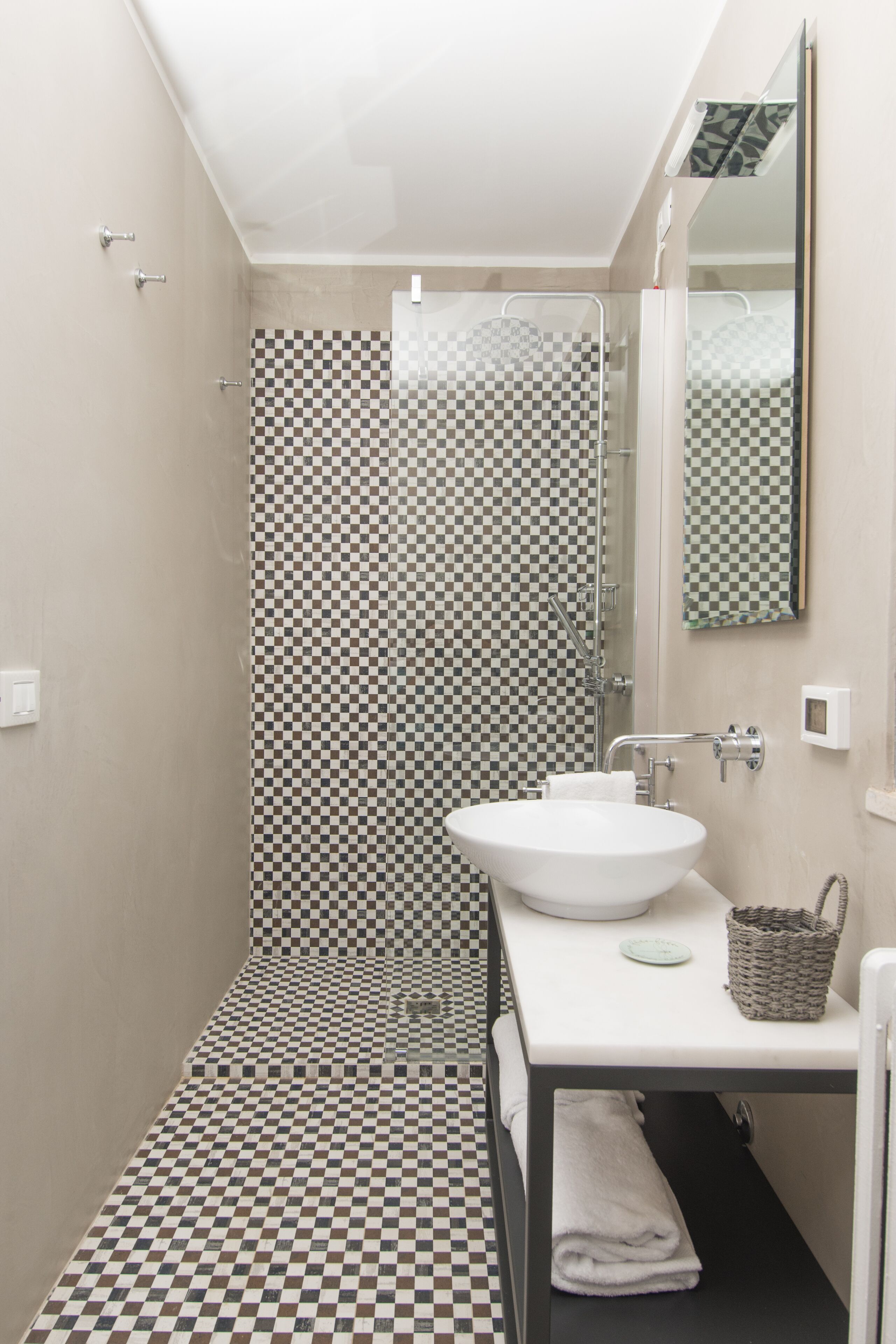 A bathroom with a checkered floor, a white sink, a mirror, and a shower area.