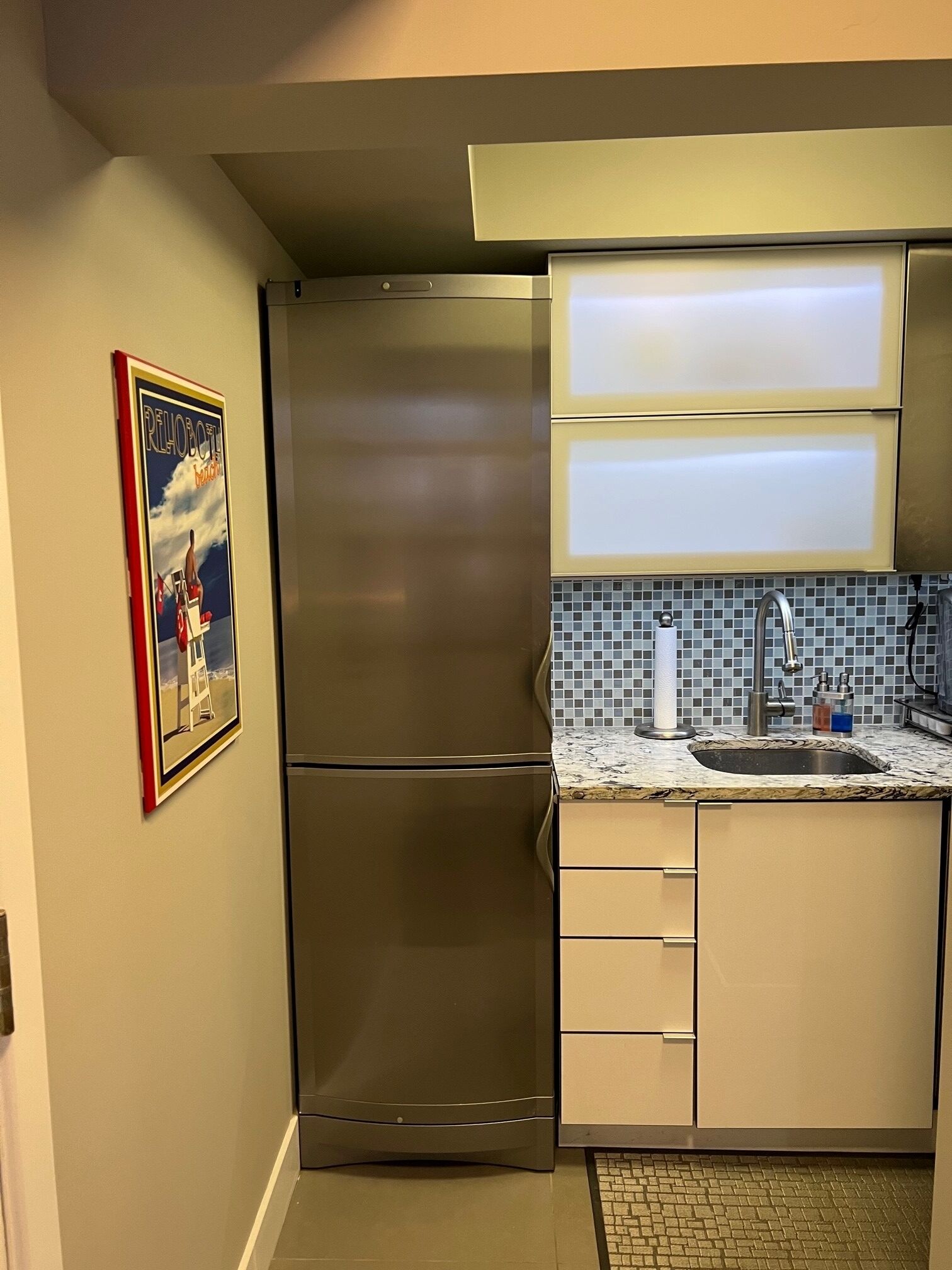 A modern kitchen with stainless steel appliances, a tiled backsplash, and a magazine on the countertop.