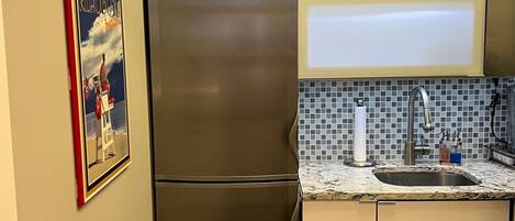 A modern kitchen with stainless steel appliances, a tiled backsplash, and a magazine on the countertop.