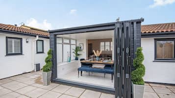 Une terrasse moderne avec une porte vitrée donnant sur un coin repas, comprenant une table, des chaises et des plantes en pot.