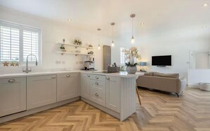 A modern kitchen with a central island, built-in cabinets, and a herringbone wood floor.