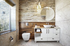 A bathroom with a wooden wall, a white sink, and a large mirror. - 3B-Barefoot-01 by bnbmehomes (Dehradun)