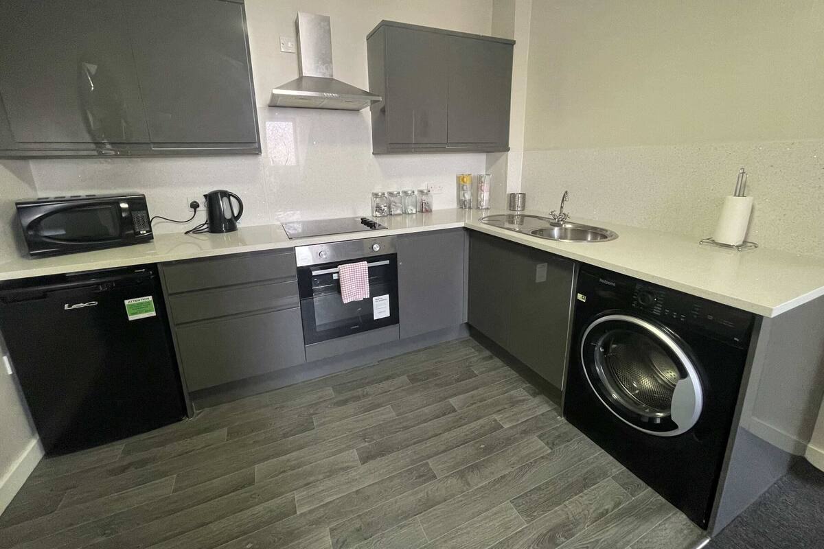 A compact kitchen with a microwave, coffee maker, oven, sink, and washing machine.